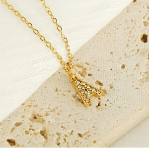 Close-up of golden letter A pendant with sparkling white zircons on a thin chain