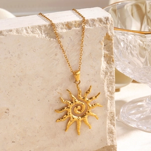 Minimalist gold sun pendant necklace with spiral center on rustic beige stone