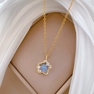 Detail of star pendant with iridescent blue-purple stone in a beige jewelry box