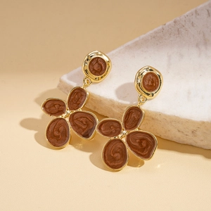 Detail of vintage gold flower earrings with brown enamel petals on light stone