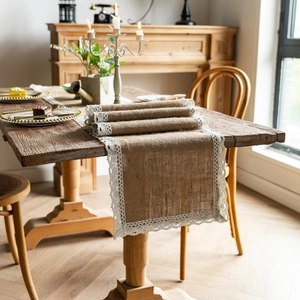 Detail of natural jute table runner with white lace edges on a vintage wooden table