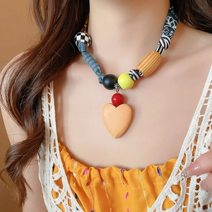 Gros plan d'un collier bohème avec pendentif cœur et perles en tissu sur un mannequin