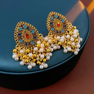 Détail de boucles d'oreilles vintage avec émail coloré et pompons en perles blanches