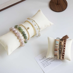 Velvet display pillow with elegant stone beads, gold bangles, and leather bracelet set