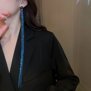 Close-up of long blue rhinestone tassel earrings with a sparkling starburst effect