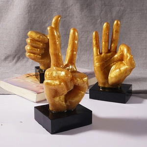 Creative gold gesture hand sculptures with thumbs up, victory, and OK sign on black bases
