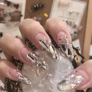 Détails de faux ongles amande avec strass argentés et perles sur une base rose nude