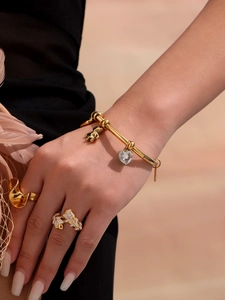 Detail showing 18k gold plated bangle with heart crystal and bear charms worn by model