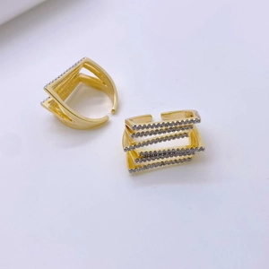 Dettaglio di anelli sovrapposti in rame placcato oro 18k con intarsio in zircone