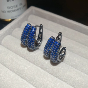 Macro shot of micro-pave dark blue zircon U-shaped hoop earrings on grey velvet