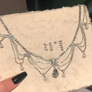 Detail of silver tassel necklace featuring sparkling rhinestones and white pearl drops