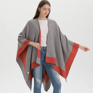 Detail shot of the color-block gray and red knitted texture on a stylish women's poncho