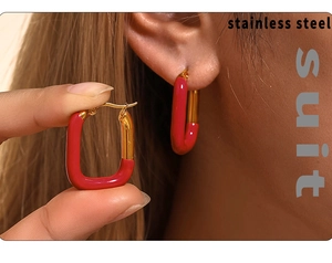 Gros plan sur les boucles d'oreilles en acier doré en forme de U avec émail rouge porté
