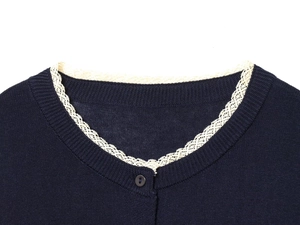 Close-up of navy knit cardigan neckline with delicate white lace trim and button detail