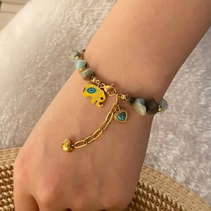 Natural stone beaded bracelet with gold elephant and heart charms worn on a wrist