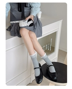 Détail de chaussettes grises en tricot avec bordure en dentelle et chaussures noires