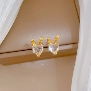 Golden bunny ear stud earrings featuring sparkling heart-shaped crystals on soft fabric