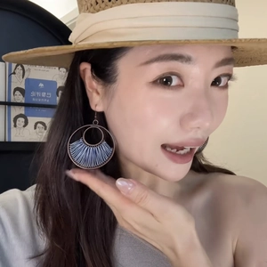 Close-up of model wearing navy blue thread-wrapped round hoop earrings with bronze frame