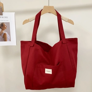Detail of red striped canvas tote bag hanging on wooden hanger with side magazine prop