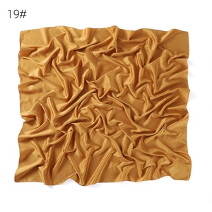 Silk satin square scarf detail view showing soft matte texture and elegant golden drape.