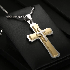 Détail du pendentif croix double couche or et argent sur un support de bijoux noir