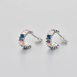 Macro shot of silver C-shaped earrings with colorful rectangular-cut zircon stones