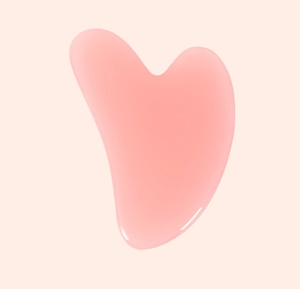 Gros plan d'un outil de massage gua sha en quartz rose en forme de cœur pour le visage