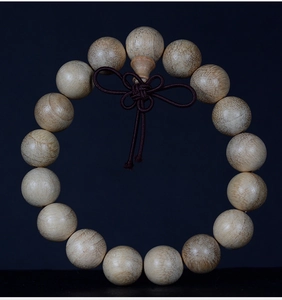 Close-up of camphor wood prayer beads showing natural grain and traditional knot