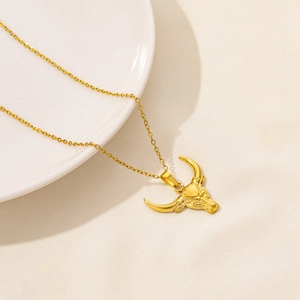 Detailed close-up of golden bull head pendant on a cross chain necklace with polished finish