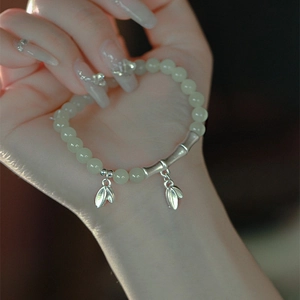 Macro detail of beaded camellia bracelet with silver bamboo tubes and leaf pendants