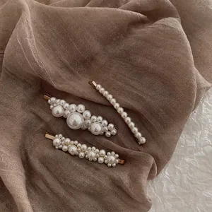 Elegant 3-piece vintage baroque pearl hair clip set with gold alloy base on soft fabric