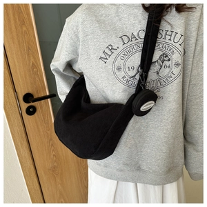 Detail of black corduroy hobo bag with small round coin purse shown on model