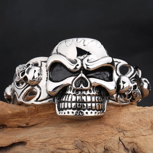 Vintage punk silver stainless steel skull bangle displayed on a natural wood block