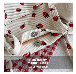 Detail of premium silver magnetic closure on off-white corduroy strawberry bucket bag