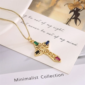 Detail of gold cross pendant with colorful zircon stones on minimalist card