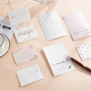 Flat lay of artistic greeting cards with sentimental quotes on a soft pink desk