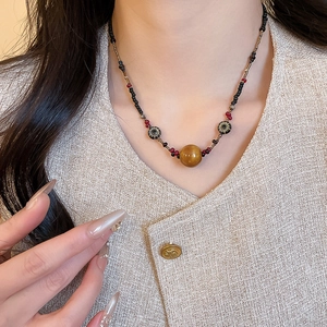 Nahaufnahme der Tigerauge-Perlenkette mit Retro-Sonnenmuster-Perlen an einem Model in Tweed