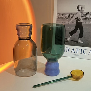 Modern colorful borosilicate glass set with grey bottle and blue base glass in warm sunset light