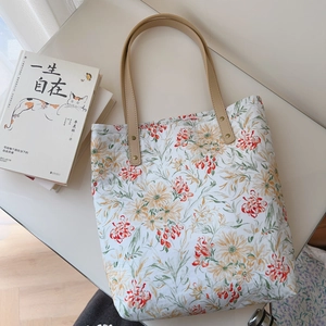 Close-up of floral cotton tote bag with leather handles and decorative book prop