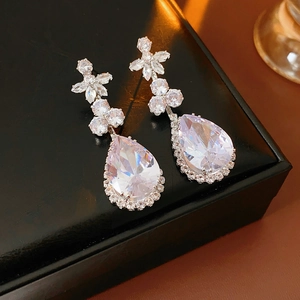 Close-up of teardrop zirconia pendant earring with floral setting on black leather box