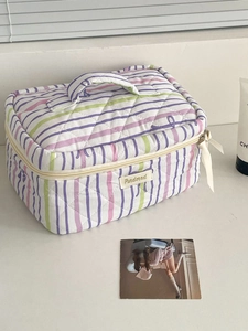 Striped quilted makeup bag with purple and green patterns and top handle for travel