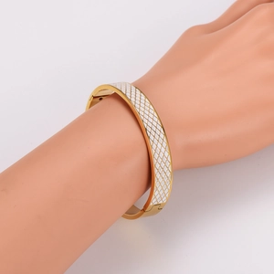 Vintage 304 stainless steel gold bangle with white enamel lattice pattern worn on wrist