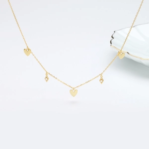 Macro shot of gold heart and diamond-shaped charms on a fine necklace chain