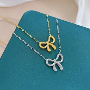 Close-up of gold and silver bow necklaces placed on a teal jewelry gift box