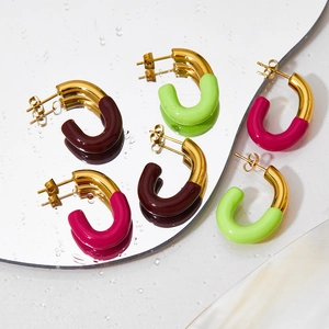 Colorful enamel C-shaped hoop earrings in red pink and lime green on mirror surface