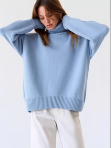 Pull à col roulé oversize bleu clair en maille douce porté avec un pantalon blanc