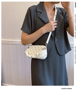 Detail of white quilted crossbody bag with golden heart studs and ruffled side design