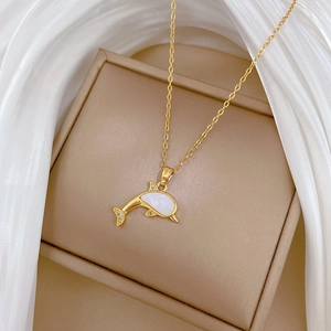 Detail of gold dolphin necklace featuring a shell inlay and shimmering crystal accents