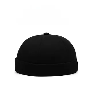 Détail du bonnet docker noir montrant la texture en coton et le logo métallique doré