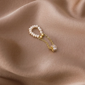 Detailed macro of gold tassel earring with freshwater pearls and square zircon accent
